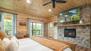 Un dormitorio con una cama grande, una chimenea de piedra y vistas a un lago.