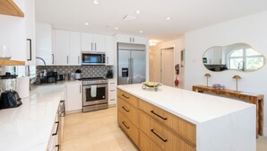 Una cocina moderna con armarios blancos, electrodomésticos de acero inoxidable y una isla de mármol.