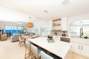 A modern kitchen with a large island, white cabinetry, and a view of the ocean.