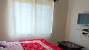 Une chambre à coucher avec un lit, une petite table et un téléviseur fixé au mur.