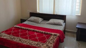 Une chambre à coucher avec un lit, une fenêtre avec des rideaux et une table de chevet.