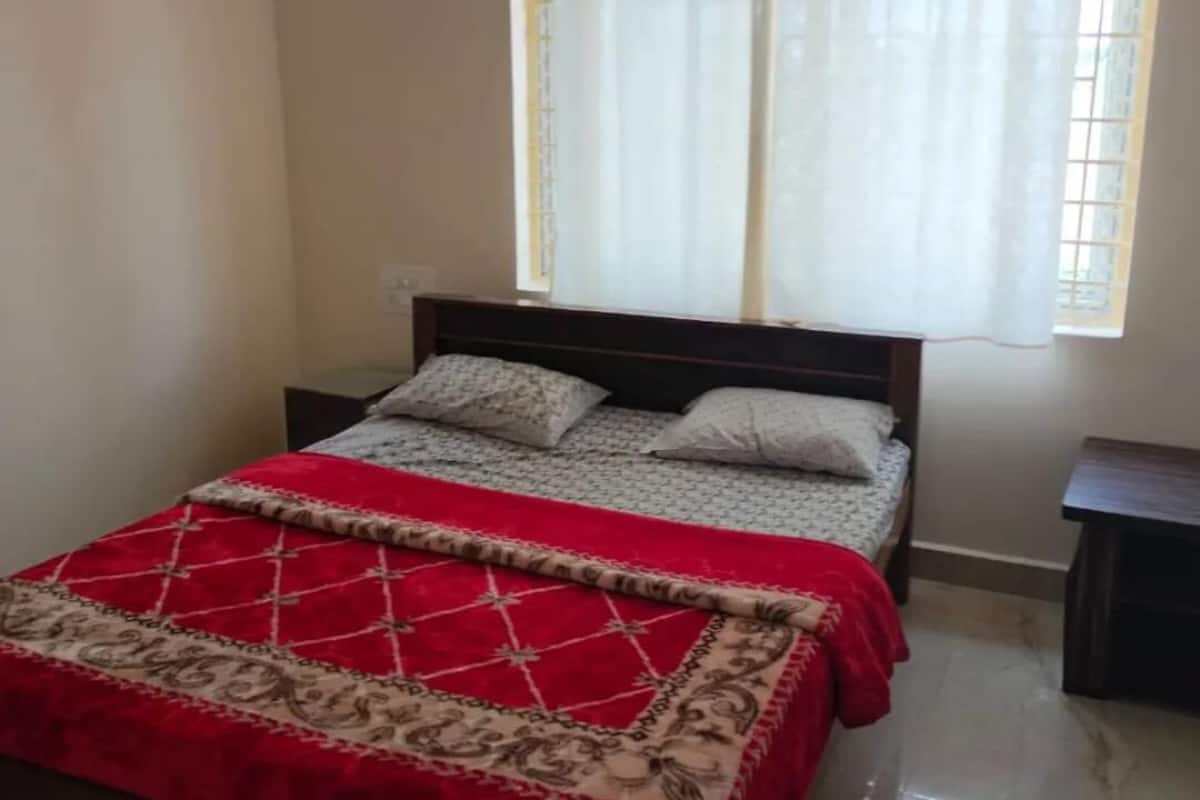 Un dormitorio con cama, cortinas en la ventana y una mesita de noche.