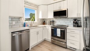 A modern kitchen with white cabinetry, stainless steel appliances, and a built-in microwave.