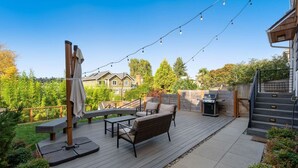 A deck with outdoor furniture, a barbecue grill, and string lights.