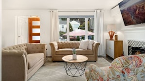 A living room with a beige sofa, a round coffee table, and a patterned armchair.