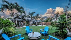 A backyard with a round table, four blue Adirondack chairs, and a bottle of wine. - Pet-Friendly 3-Bedroom Home with Pool (Bonita Springs)