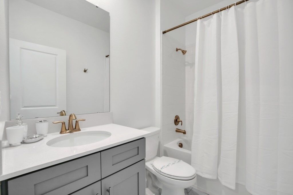 Une salle de bain moderne avec un lavabo blanc, des robinets dorés et des toilettes blanches.