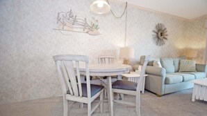 A dining area with a round table and four chairs, a sofa, and a decorative wall piece.