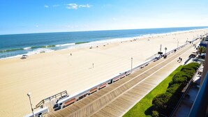 A beach with a wooden boardwalk, beach chairs, and umbrellas.