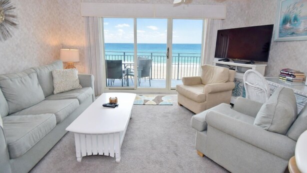 A hotel room with a balcony, a television, and a seating area with two sofas and a coffee table.
