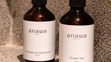 Zwei Flaschen Anawa Shampoo, Conditioner und Duschgel auf einer strukturierten Oberfläche.