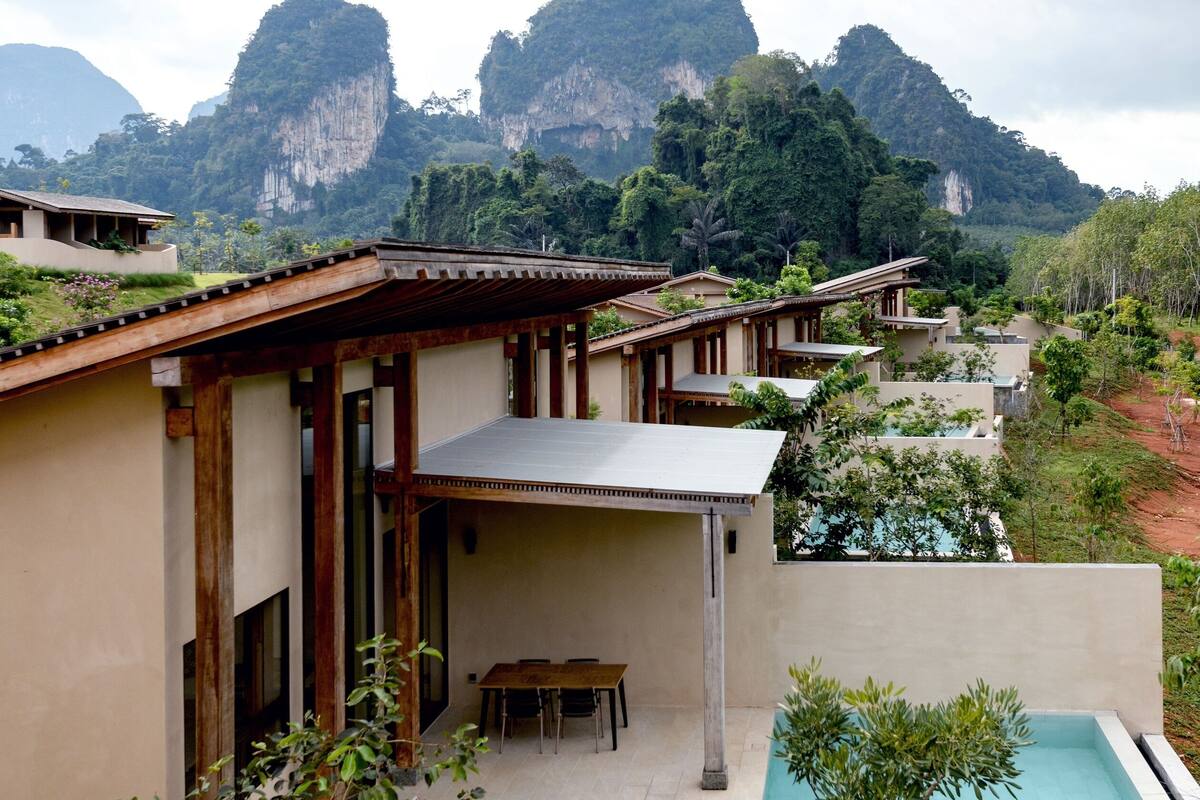 Un moderno resort con piscina, terraza de madera y vistas a la montaña.