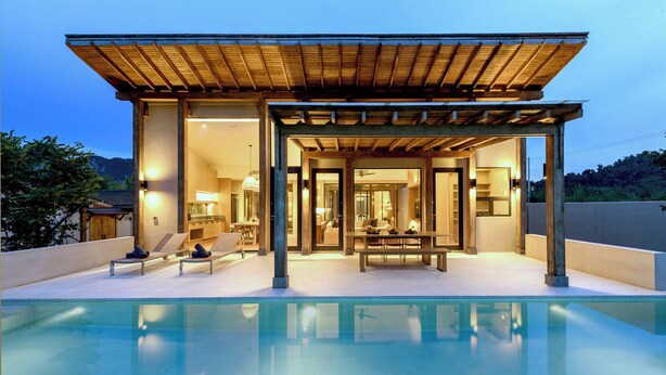 Une maison moderne avec piscine, dotée d’un patio couvert comprenant un espace salon et une table à manger.