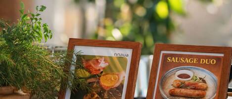 Una mesa con un menú enmarcado, una planta en maceta y nueces decorativas.