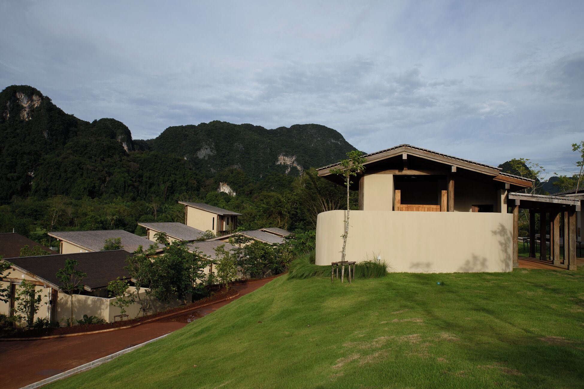 A residential area with houses, a grassy lawn, and a mountainous backdrop.