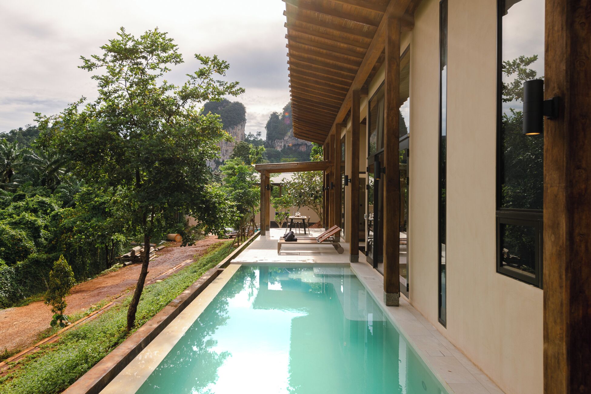 A modern poolside area with a clear view of the surrounding landscape, including trees and a distant mountain.