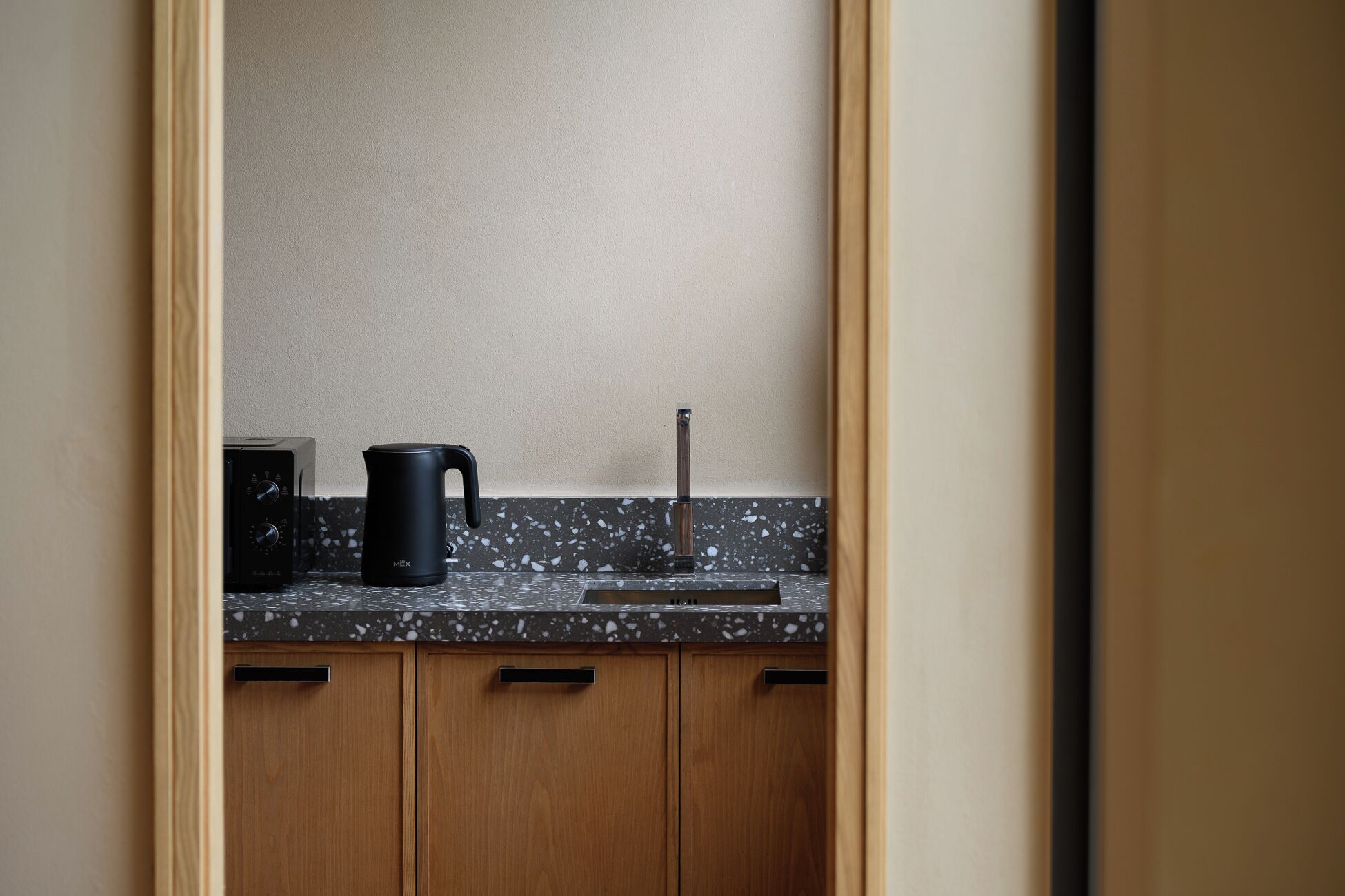 Une cuisine dotée d’un plan de travail en granit, d’une machine à café noire et d’un robinet en acier inoxydable.