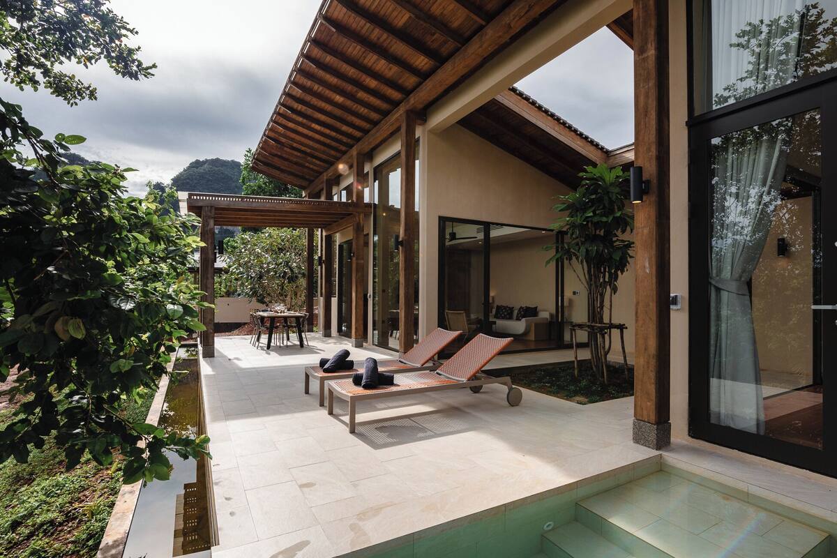 Un patio moderno al aire libre con piscina, sillas de descanso y zona de comedor.
