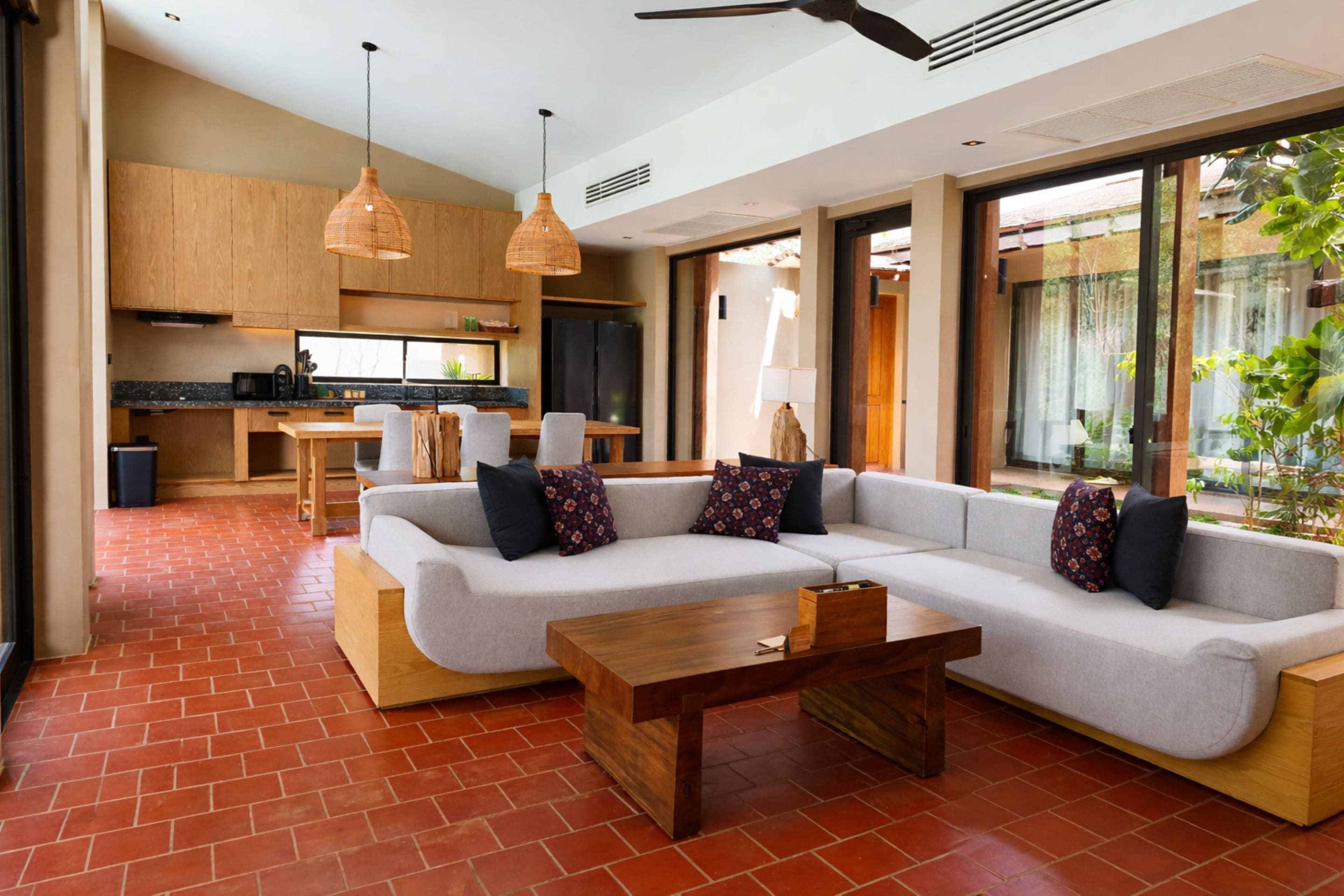 Una sala moderna con un sofá modular, una mesa de centro de madera y una cocina al fondo.