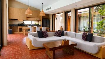 Una sala moderna con un sofá modular, una mesa de centro de madera y una cocina al fondo.