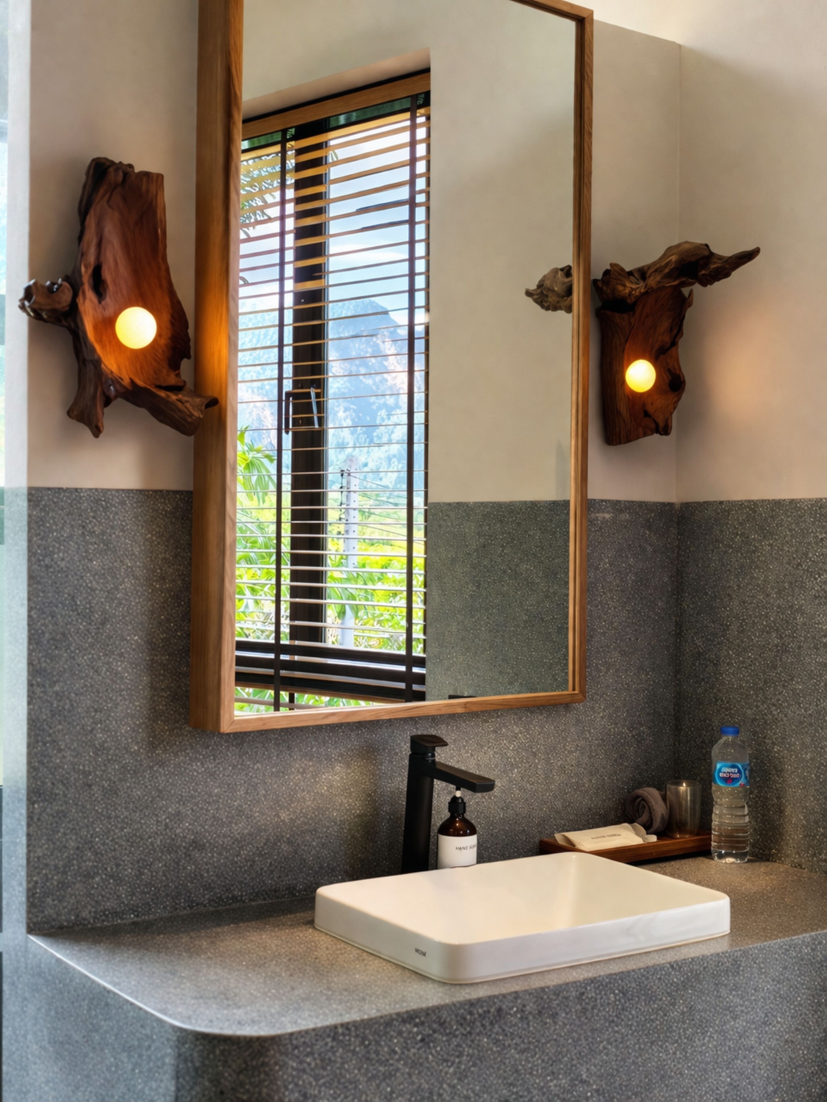 A bathroom with a large mirror, wooden wall decor, a white sink, and a bottle of hand soap.