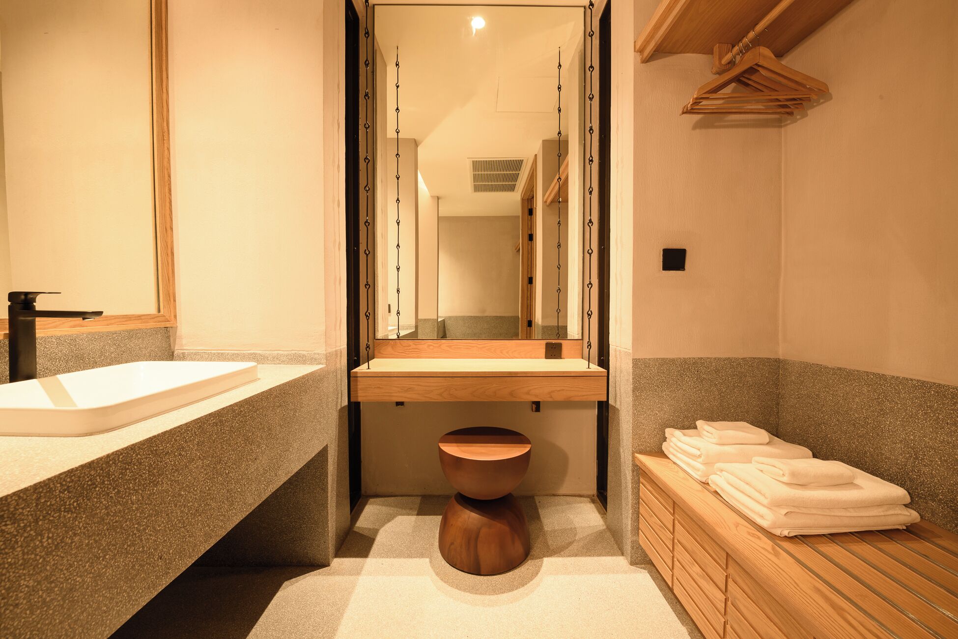 A modern bathroom with a wooden vanity, a sink, a mirror, and a wooden stool.