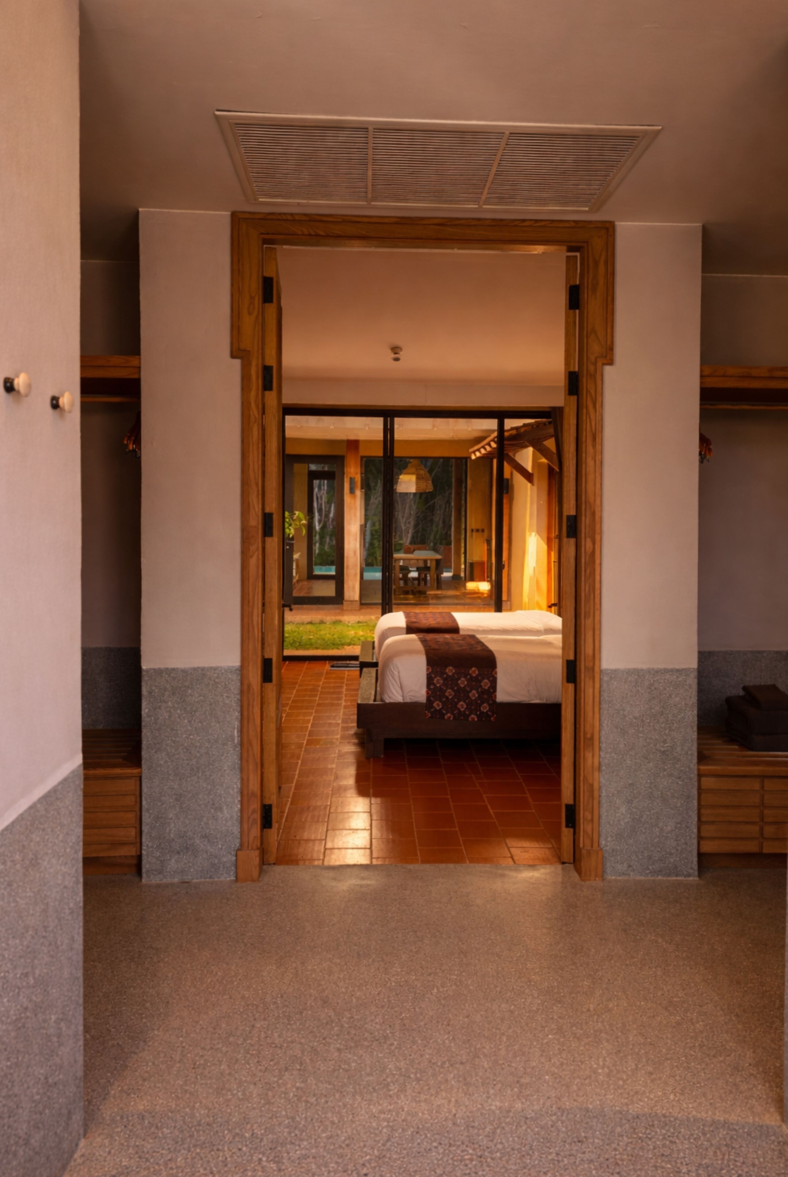 Quarto de hotel com uma cama, uma porta de madeira e vista para o exterior.