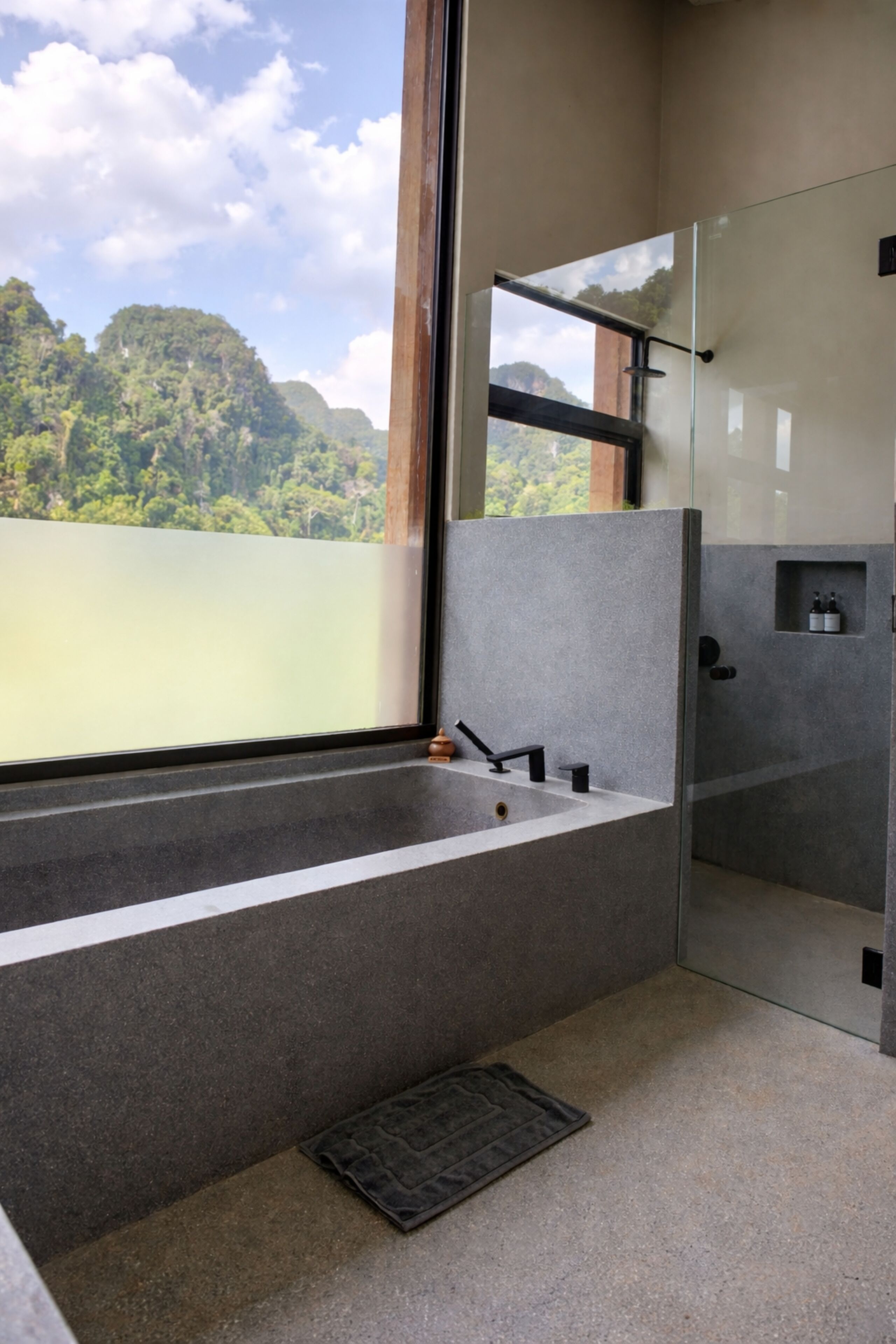Un baño moderno con cabina de ducha de vidrio, una bañera y vistas a un paisaje montañoso.