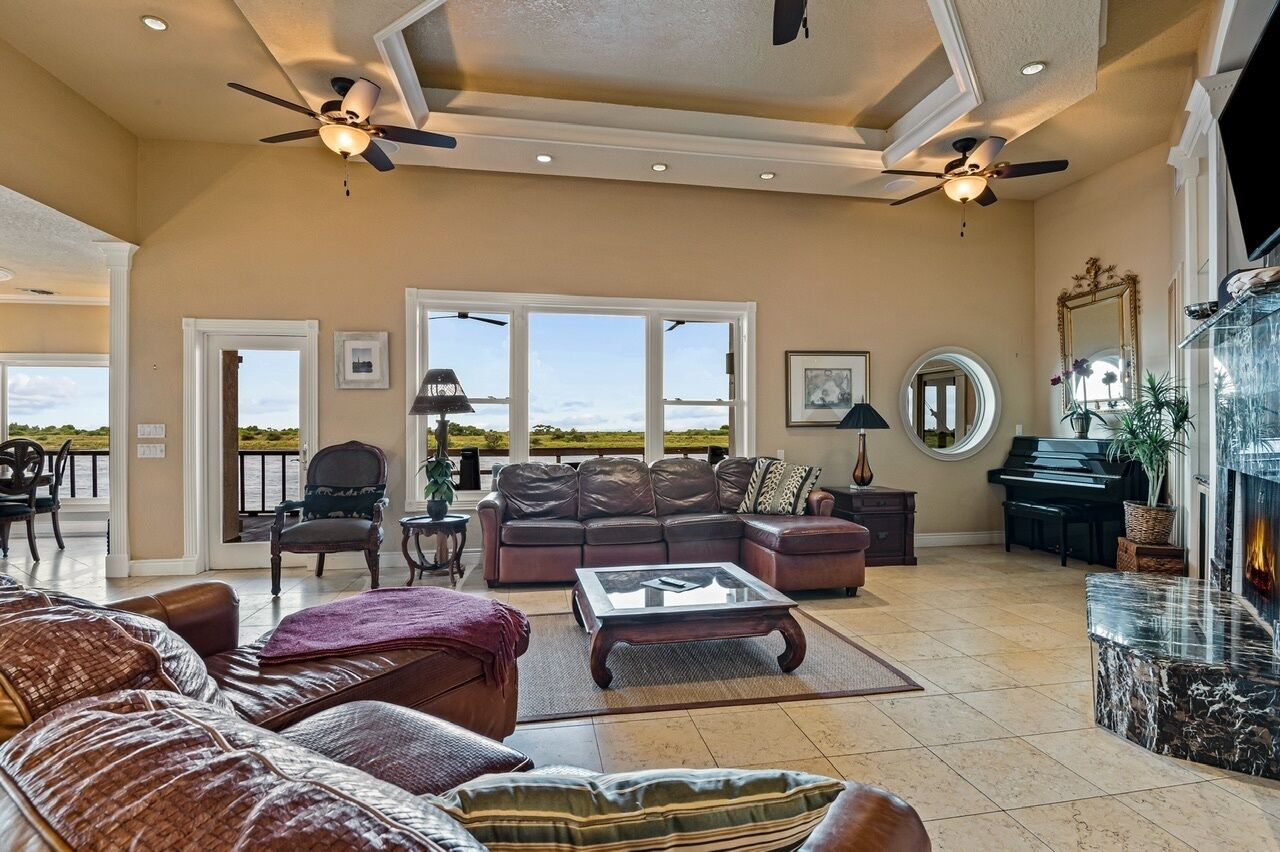 A spacious living room with a fireplace, a piano, and a view of the outdoors.