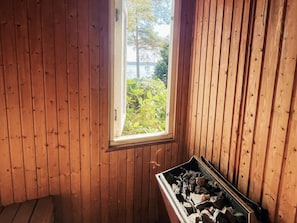 Una habitación con paredes de madera, una ventana y una chimenea con leña.