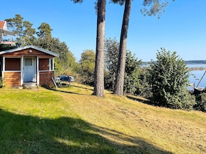 A small cabin with a door and steps, a table with chairs, and a view of a body of water.