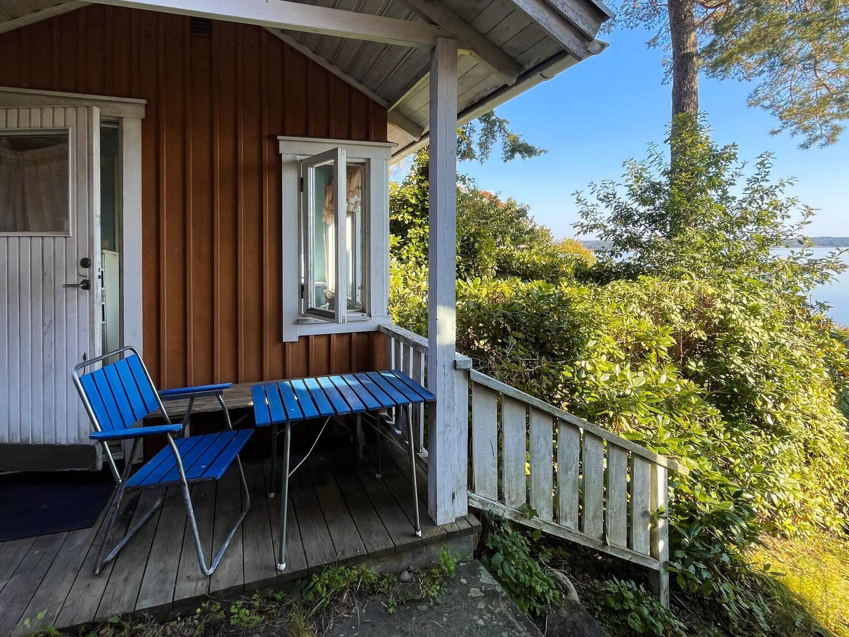A wooden building with a porch, a table, and two chairs.