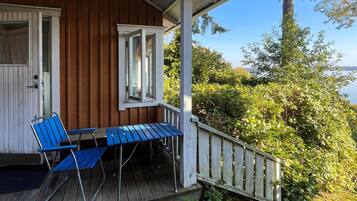 A wooden building with a porch, a table, and two chairs.