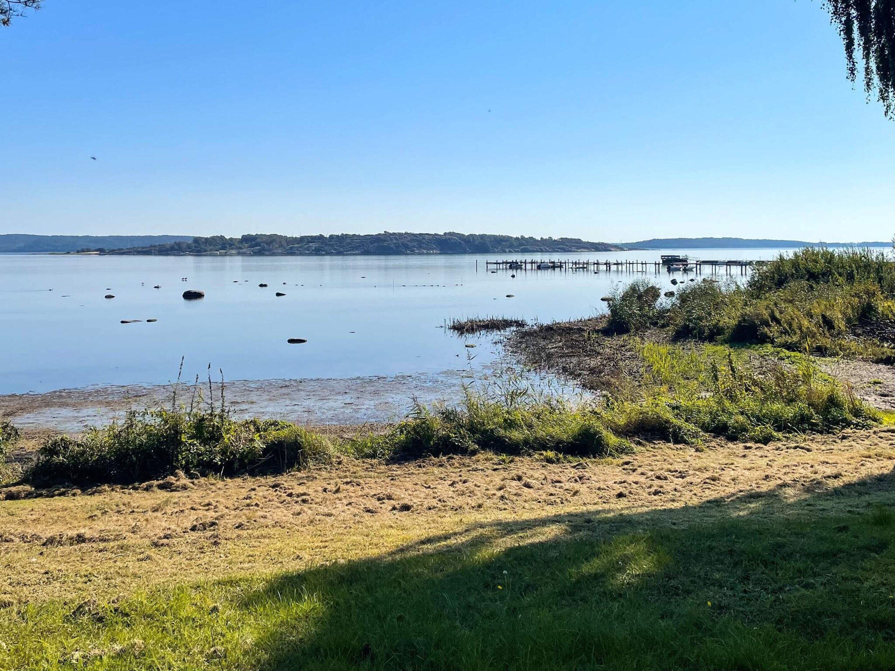 Een rustig meer met een zandstrand en een steiger die het water in reikt.