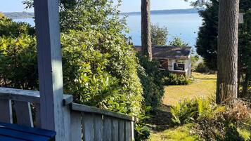 A wooden deck with a view of a lake and a small building with a porch.