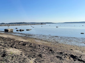A coastal landscape with a rocky shoreline, calm water, and a distant pier. - 4 Person Holiday Home in Onsala (Gottskar)