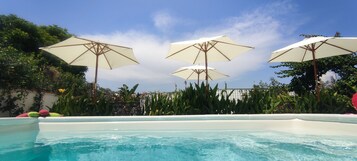 Una piscina al aire libre, sombrillas, sillones reclinables de piscina