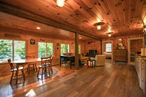 L’intérieur de la cabane est doté de murs et de planchers en bois, d’un coin repas avec une table et des chaises, d  ’un espace de détente avec un canapé et un téléviseur, et d’une cuisine équipée de placards et d’appareils électroménagers.