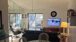 A modern living room with a dining area, a ceiling fan, a TV, and a view of the outdoors. - Great Location 2 BR, 2 Bath condo in quiet community, MINUTES from the beach!!   (Fort Myers)