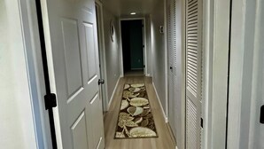 A hallway with white doors, a patterned rug, and a ceiling light. - Great Location 2 BR, 2 Bath condo in quiet community, MINUTES from the beach!!   (Fort Myers)