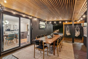 A modern dining area with a wooden table and chairs, a glass partition, and a view of the kitchen.