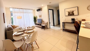 A modern living room with a dining area, a TV, and a kitchen. - Prime Location 2 BDR Apt, Pool, GYM, ground floor, Walkable to Everything (Santa Ana)