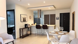A modern kitchen with a dining area, featuring a kitchen island, chairs, and a table set for two. - Prime Location 2 BDR Apt, Pool, GYM, ground floor, Walkable to Everything (Santa Ana)