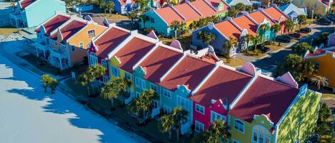 A coastal area with colorful buildings, a beach, and parked vehicles.