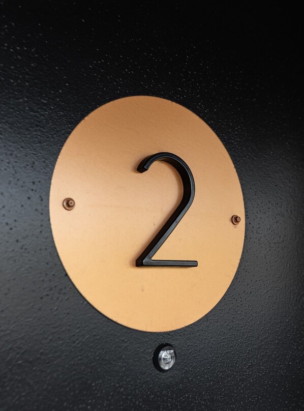 A circular sign with the number 2, mounted on a textured surface.