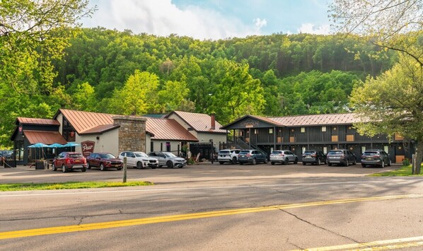A parking lot with multiple cars, a building with a sign that reads 'Lincoln', and a forested hill in the background.