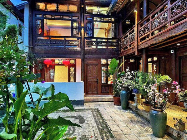 Il s’agit d’un bâtiment traditionnel doté d’une façade en bois, de nombreux balcons et d’une cour bien entretenue agrémentée de plantes en pot et d’un sol carrelé.