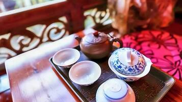 A tray with a teapot, two cups, and a small container on a table with a patterned tablecloth.