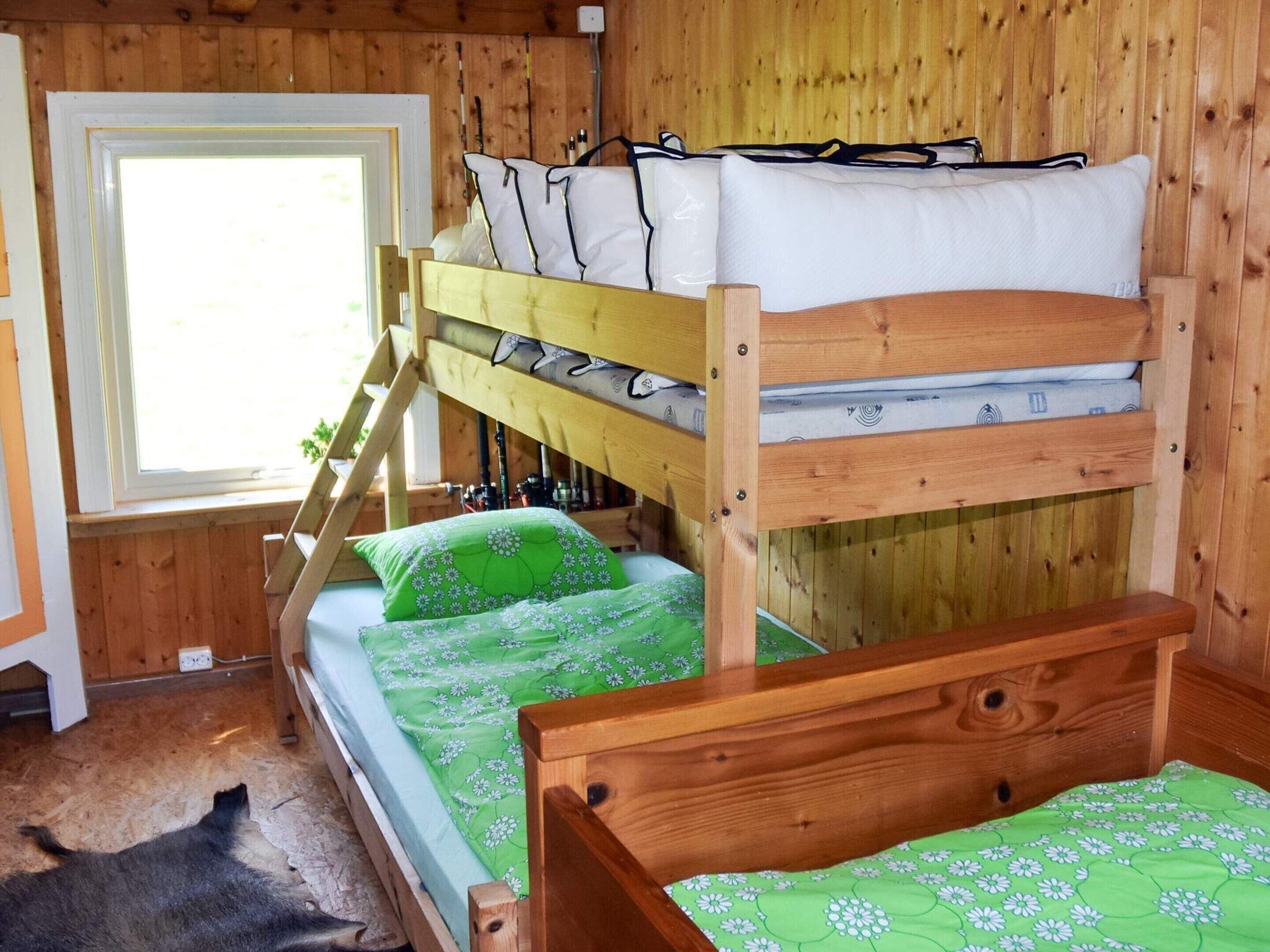 A bunk bed room with a window, wooden walls, and a small rug.