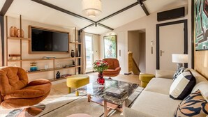 Een moderne woonkamer met een grote televisie, comfortabele zitplaatsen, een bijzettafeltje en een boekenkast.